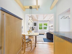 Una cucina moderna con mobili in legno, un'area pranzo con tavolo e sedie, e vista all'esterno tramite una porta.