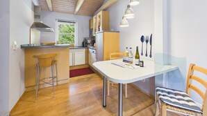 Een compacte keuken met een eethoek, houten vloeren en een raam voor natuurlijk licht.