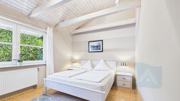 Een slaapkamer met een bed, nachtkastjes, een raam en een radiator.