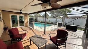 Una veranda coperta con piscina, sedie rosse, un tavolo e una ventola a soffitto.