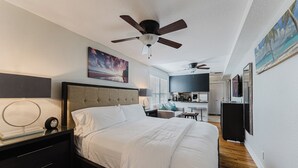 Een slaapkamer met een groot bed, een plafondventilator, een nachtkastje en een bureau.