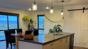 Una cucina moderna con isola centrale, ampie finestre e lampade a sospensione.