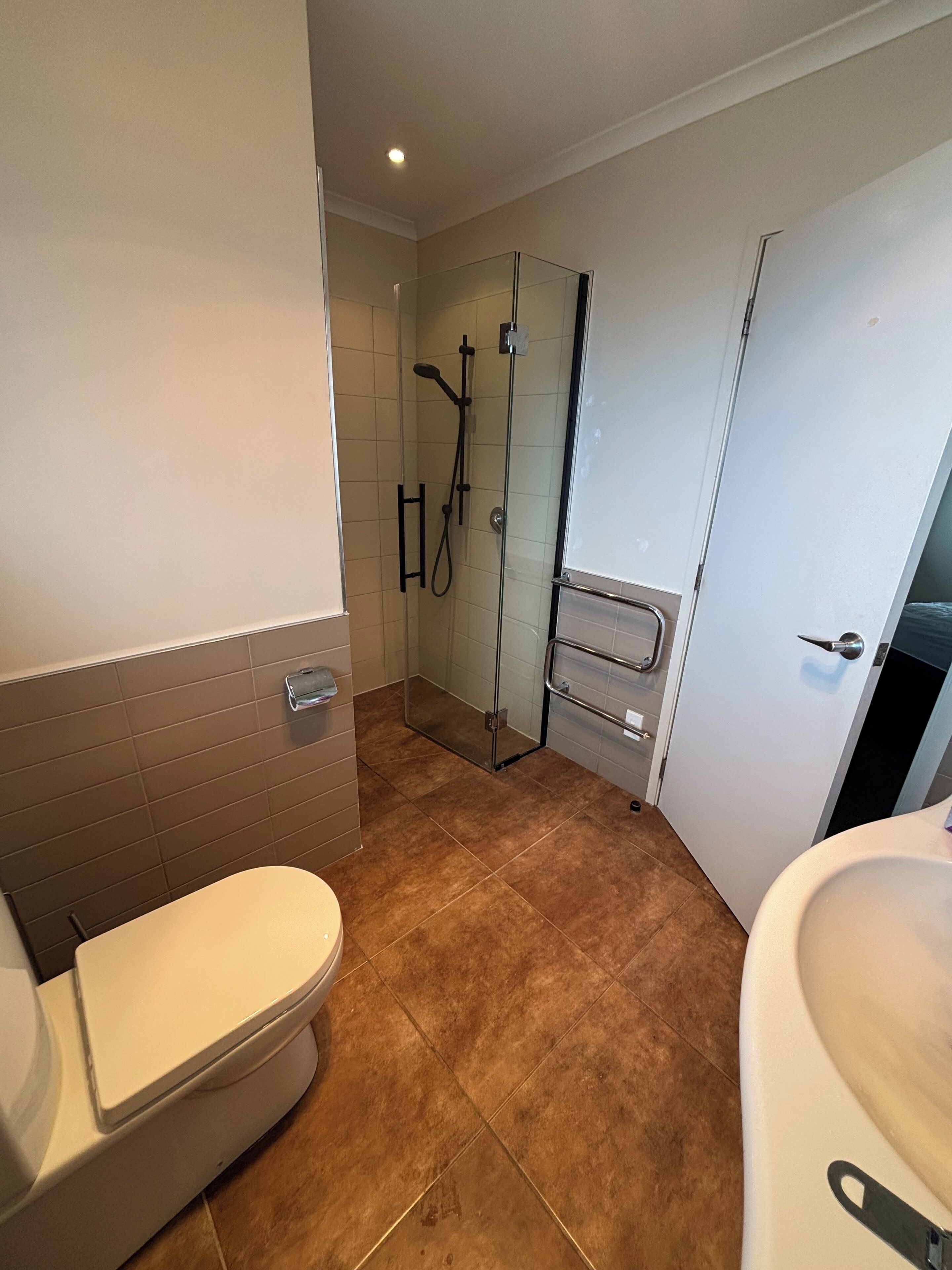 A bathroom with a toilet, a glass shower enclosure, and a sink.
