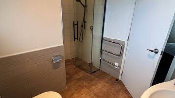 A bathroom with a toilet, a glass shower enclosure, and a sink.