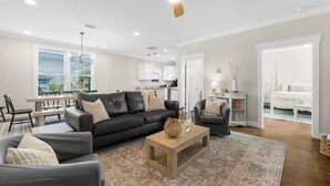 A modern living room with a black sofa, a wooden coffee table, and a ceiling fan.