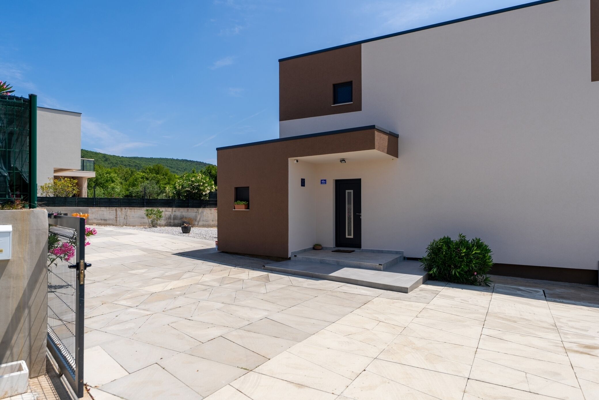 Un bâtiment moderne doté d’un toit plat, d’une petite entrée et d’une cour pavée.