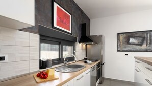 Una cocina moderna con un lavamanos de acero inoxidable, encimera de madera y armarios blancos.