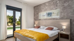 Un dormitorio moderno con una cama de madera, una manta amarilla, una mesita de noche con una lámpara y un cuadro en la pared.