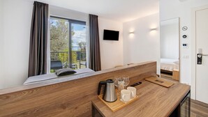 A modern hotel room with a bed, a wooden desk, a TV, and a balcony with a view. - Room 'Insula Felix Matr Lake View' with Shared Terrace, Wi-Fi and Air Conditioning (Moniga del Garda)