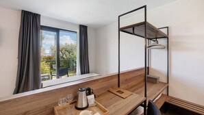 A modern room with a wooden desk, a coffee maker, and a tray with glasses and cups.