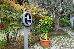 An electric vehicle charging station in a garden with a potted plant nearby. - Room 'Insula Felix Tripla Vista Lago' with Shared Terrace, Wi-Fi and Air Conditioning (Moniga del Garda)