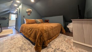 Un dormitorio con una cama grande, un aparador y un televisor.