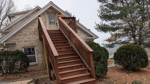 Una casa con una escalera de madera que conduce a la puerta principal, rodeada de grava y piedras pequeñas.