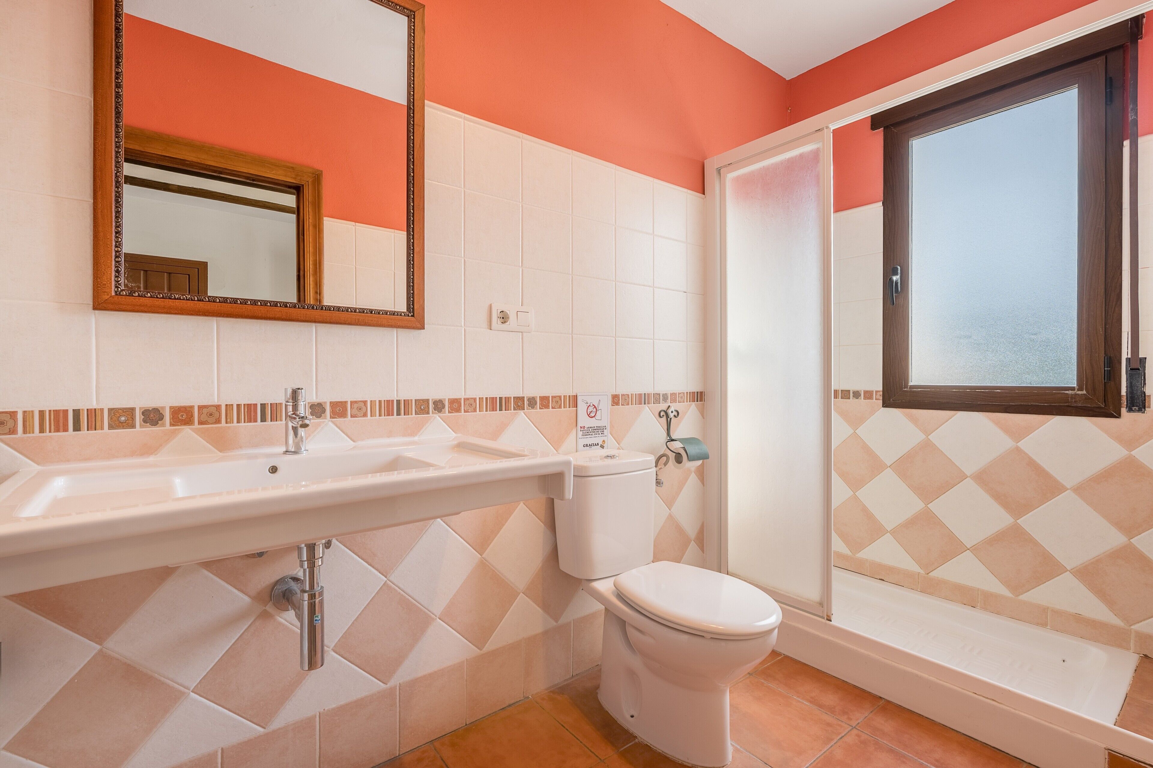 Un baño con lavamanos, inodoro y bañera, con piso y paredes de azulejos.