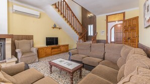 A living room with a sectional sofa, a fireplace, a television, and a staircase. - Country House 'Ana - Cortijo Puerta' with Private Pool, Wi-Fi and Air Conditioning (Órgiva)
