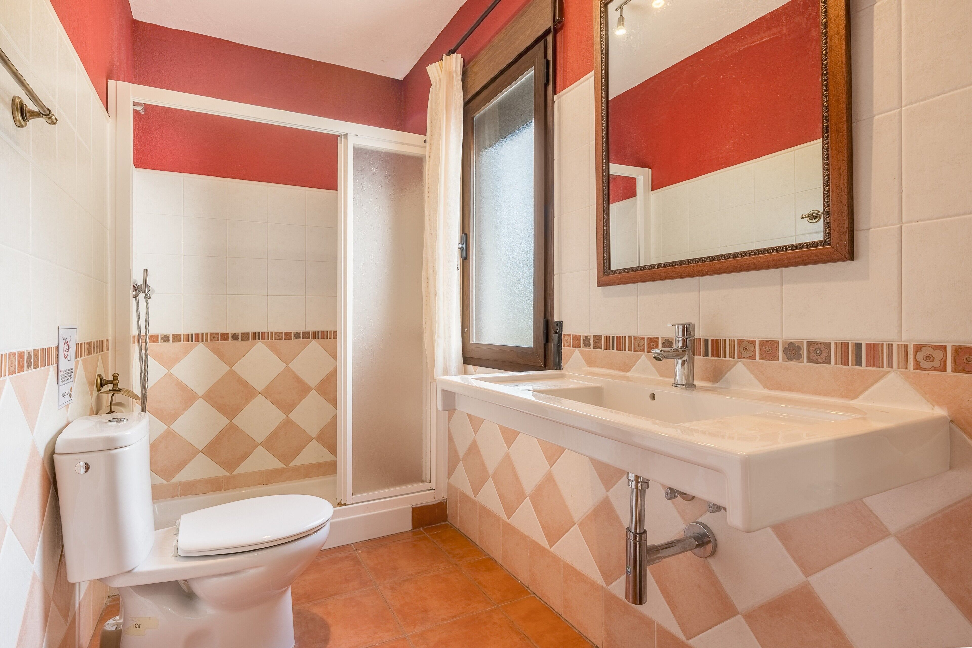 Un baño con inodoro, lavabo, ducha y espejo.
