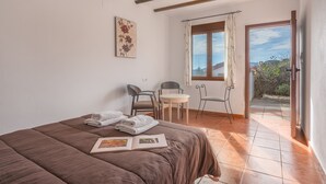 A bedroom with a bed, a desk, chairs, a window, and a door leading to an outdoor area. - Country House 'Ana - Cortijo Puerta' with Private Pool, Wi-Fi and Air Conditioning (Órgiva)