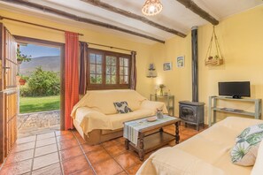 A cozy room with a sofa, a small table, a TV, and a fireplace. - Country House 'Lavanda' with Mountain View, Shared Pool and Wi-Fi (Órgiva)