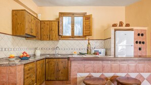 A kitchen with wooden cabinets, a refrigerator, and a tiled backsplash.