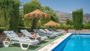 A poolside area with lounge chairs, thatched umbrellas, and a clear view of the surrounding landscape.