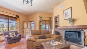 A living room with a fireplace, two sofas, a coffee table, and a large window with a view of the desert.