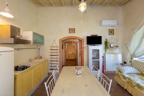 A compact kitchen with a dining table, a TV, and a sofa.