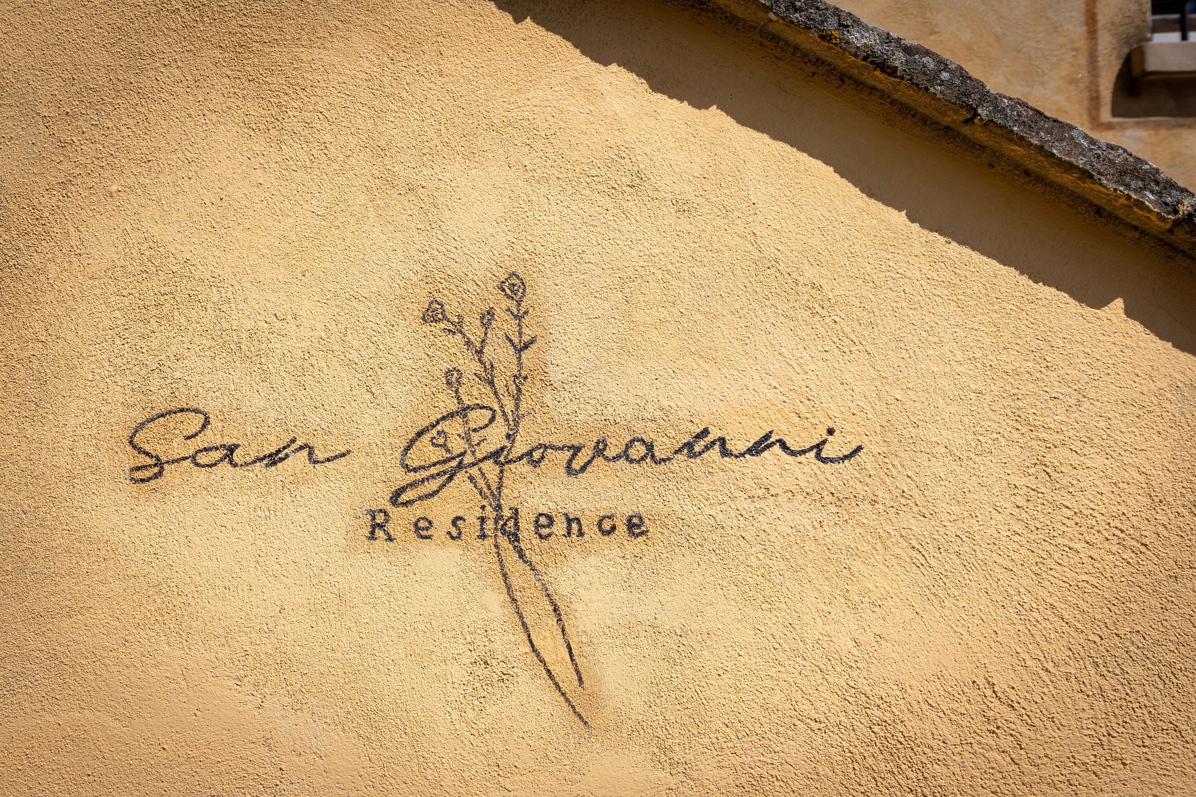 A building facade with the inscription 'San Giovanni Residence' and a floral design.