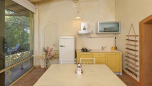 Une cuisine équipée d’un réfrigérateur, d’une cuisinière, d’un évier et d’un téléviseur fixé au mur.
