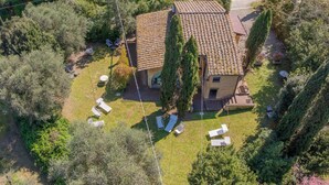 An aerial view of a house with a tiled roof, surrounded by trees and a grassy yard with outdoor furniture. - San Giovanni R. Apartment 1 Dantea with Private Garden, Wi-Fi, and Air Conditioning (Peccioli)
