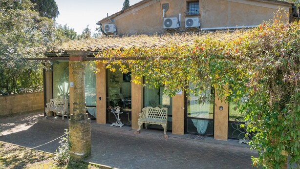 A building with a covered patio, outdoor seating, and air conditioning units. - San Giovanni R. Apartment 1 Dantea with Private Garden, Wi-Fi, and Air Conditioning (Peccioli)