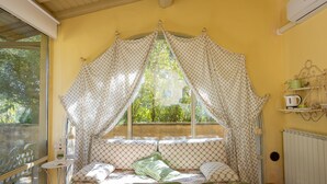 Ein Zimmer mit einem Bett, einem kleinen Tisch, einem Fenster mit Vorhängen und einer Heizung.