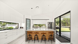 A modern kitchen with a large island, bar stools, and a view of the outdoors.