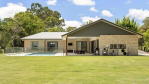 A modern house with a swimming pool, outdoor seating, and a barbecue area.