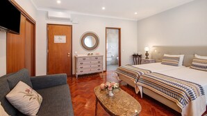 Una habitación de hotel con una cama grande, un sofá, un aparador, un espejo y un televisor.