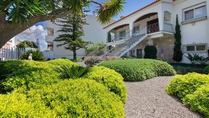 A multi-story building with a central staircase, surrounded by well-manicured hedges and a gravel path. - Milreu Guesthouse - Room "Raízes" (Estói)