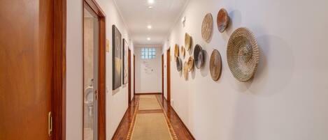 A hallway with wooden doors, a patterned rug, and wall-mounted woven baskets.