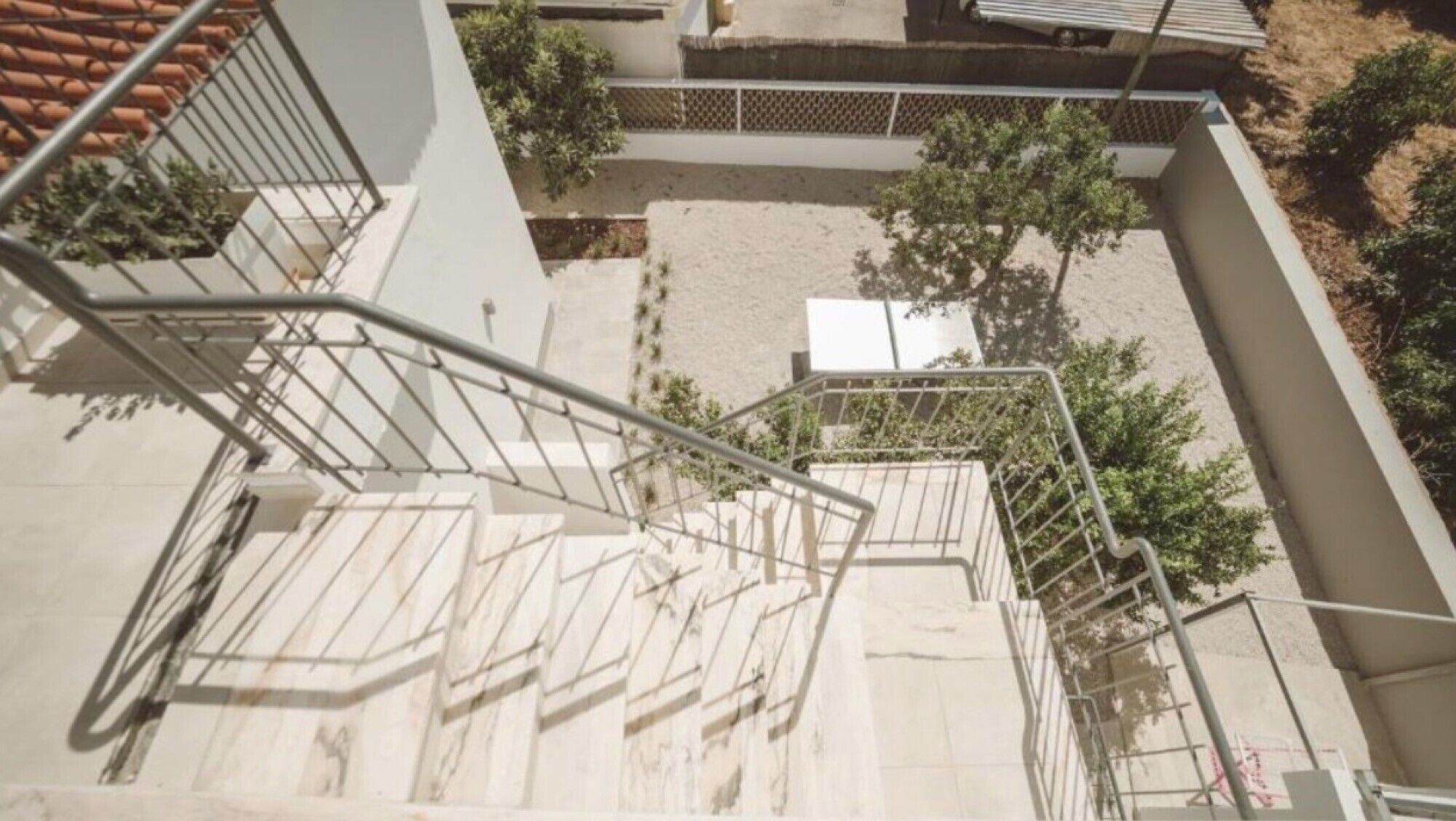 A set of outdoor stairs leading to a building with a tiled roof and a fenced courtyard.