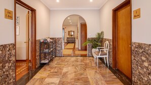 A hotel hallway with a marble floor, a reception desk, a plant, and a door labeled '5 Alerim.'