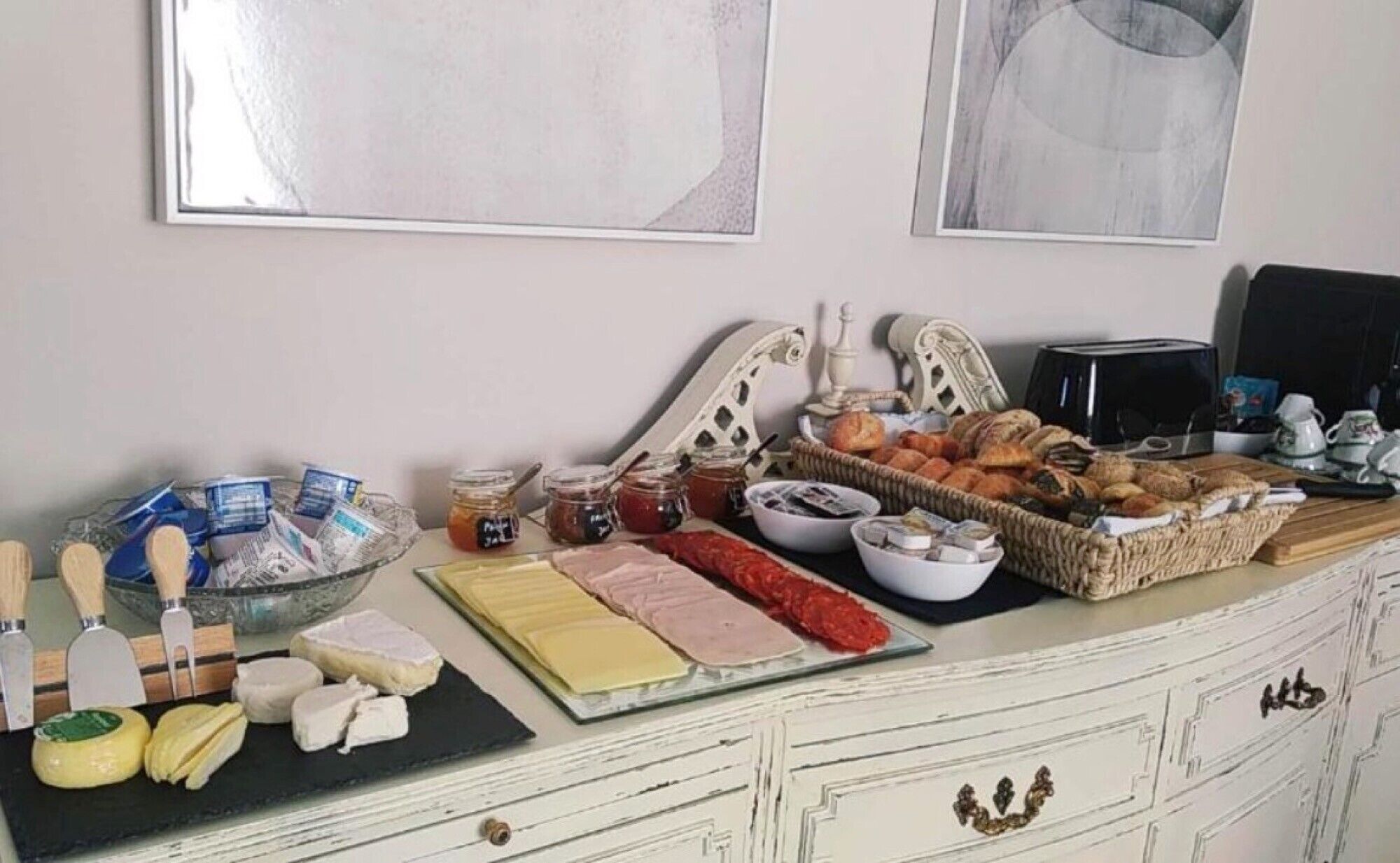 A buffet table with various cheeses, meats, and pastries.