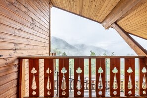 Un balcon en bois offrant une vue sur les montagnes et un ciel nuageux.