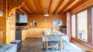Puinen sisustus, jossa on ruokapöytä neljälle, keittiöalue ja suuri ikkuna.