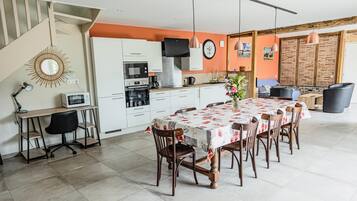 A modern kitchen with white cabinets, a dining area with a floral tablecloth, and a staircase.