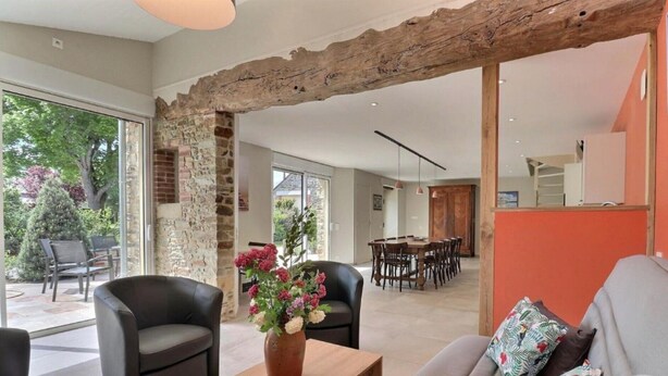 Un amplio salón con pared de piedra, una mesa de comedor y muebles modernos.
