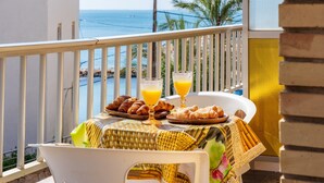 Un balcón con una mesa dispuesta para el desayuno, con vistas al mar.