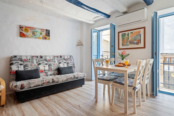 Una habitación con sofá, mesa de comedor, sillas y un cuadro en la pared.
