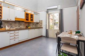 Una cocina moderna con armarios blancos, encimera de madera y una zona de comedor con mesa y sillas.
