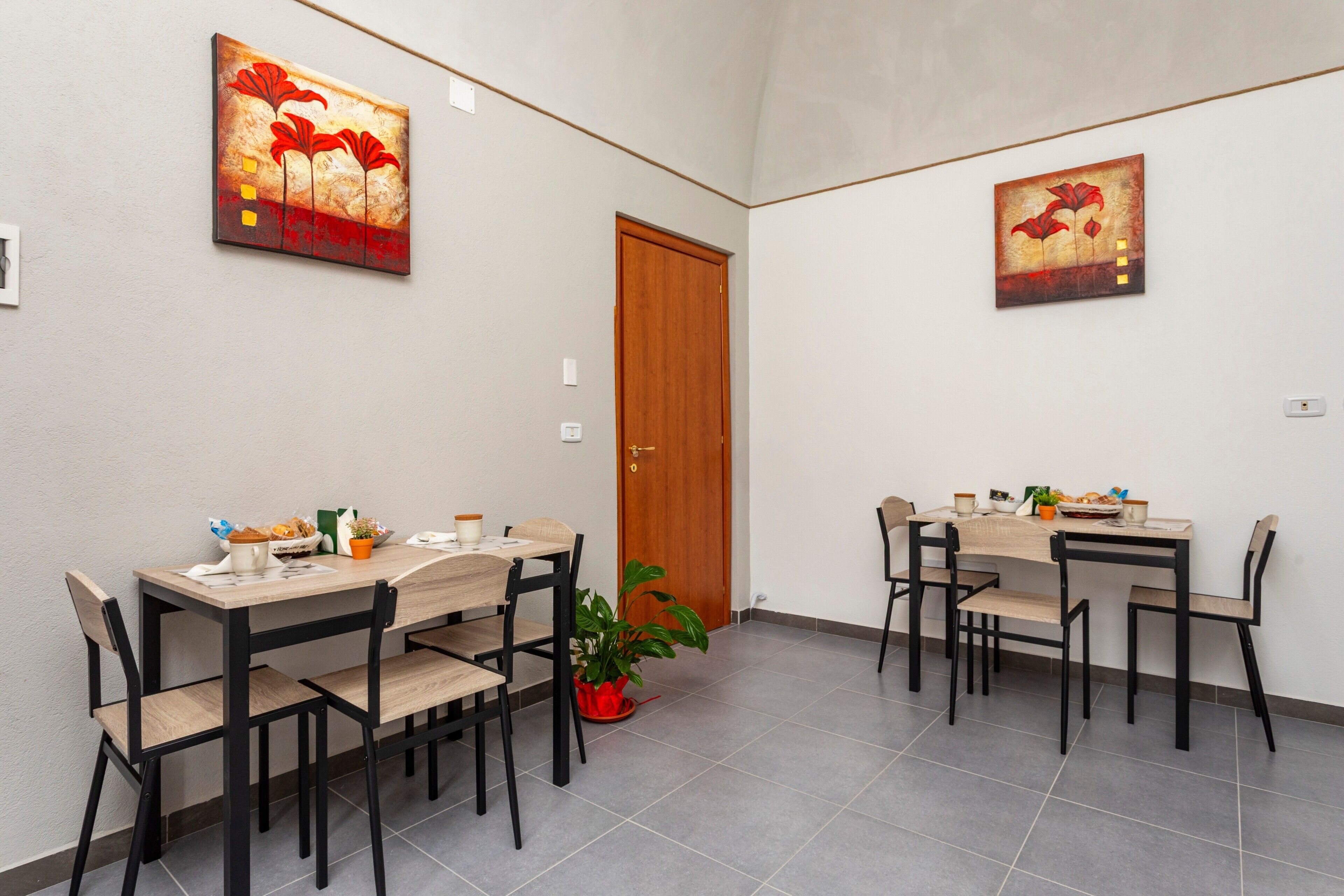 A dining area with two tables, chairs, and a potted plant.