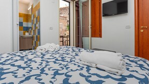Een slaapkamer met een bed, een televisie en een badkamer, zichtbaar door een geopende deur.