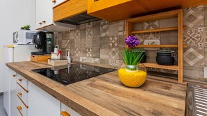 Een moderne keuken met een houten aanrecht, een ingebouwde magnetron en een glazen vaas met bloemen.