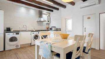 Cuina moderna amb zona de menjador, bigues de fusta i rentadora.